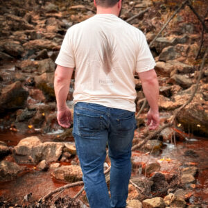 Man walking on rocky path near stream.