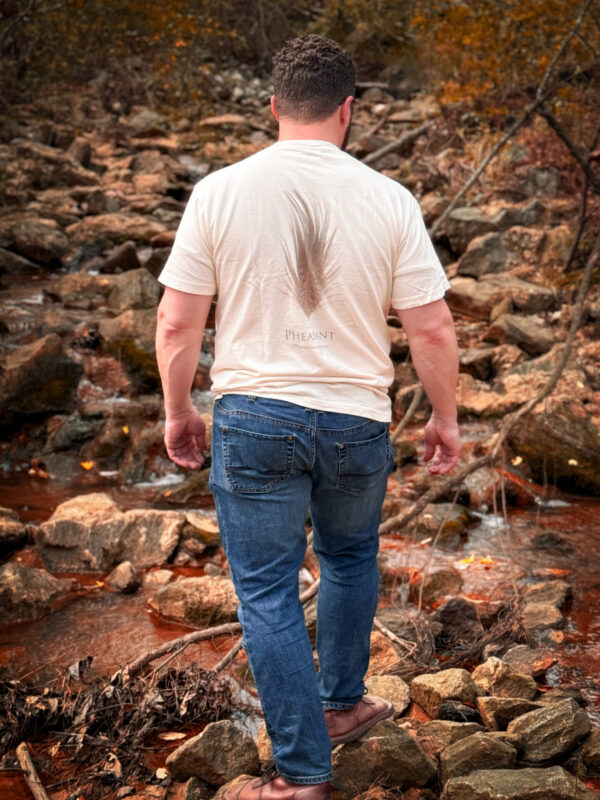 Man walking on rocky path near stream.
