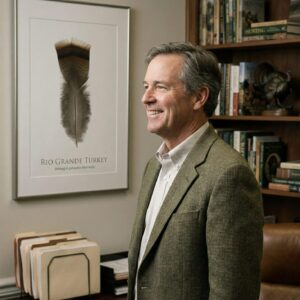 rioGrandManwithArt Man in office with Rio Grande turkey poster.